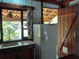 瓜尔达恩巴Recanto das Bromélias Chalés的厨房配有冰箱、水槽和窗户。