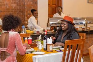 基苏木Desert Rose Resort Kisumu的坐在桌子上的戴帽子的女人
