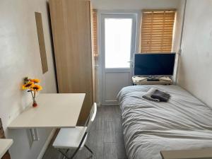 伦敦Rooms at EEJ homes的小房间设有床、书桌和电视