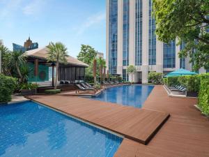 曼谷Sofitel Bangkok Sukhumvit的一座带木甲板和大楼的游泳池