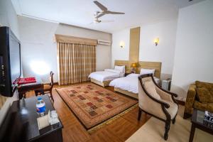 白沙瓦Shelton House Peshawar的酒店客房设有一张床、一张书桌和一台电视机。