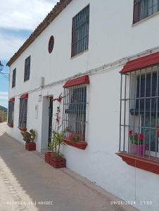 查兹拉德拉谢拉Casa El Azahin的白色的建筑,有红色的窗户和植物