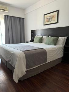布宜诺斯艾利斯Duomi Hotel Buenos Aires的一间卧室配有一张带白色床单和绿色枕头的大床。