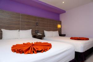 坎昆卡维亚酒店的配有橙色床单的酒店客房内的两张床