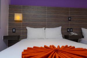 坎昆卡维亚酒店的一间卧室配有一张大床,上面有橙色毯子