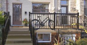 多伦多Modern 1BR Condo - near Trinity Bellwoods Park的停在房子前面的围栏上的自行车