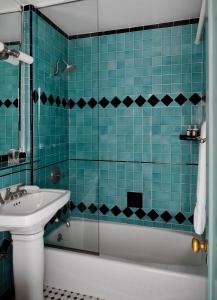 洛杉矶乔治亚酒店的蓝色瓷砖浴室设有浴缸和水槽