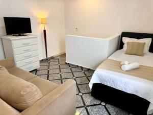 瓜鲁柳斯15 min Aeroporto Internacional de Guarulhos, 10 min centro GRU的一间卧室配有一张床、一张沙发和一台电视。