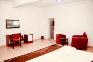 阿布贾Executive Gold Hotel的一间卧室配有红色椅子、一张床和一张桌子