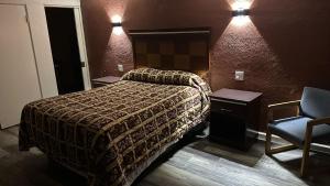罗斯威尔Deluxe Inn Of Roswell的配有一张床和一把椅子的酒店客房