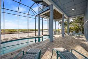 迈尔斯堡海滩Papa's Boat House - 8214 Estero Blvd home的客房设有游泳池、椅子和窗户。