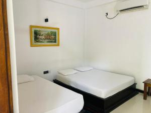 波隆纳鲁沃Hotel Siyathma polonnaruwa的配有白色墙壁的小客房内的两张床