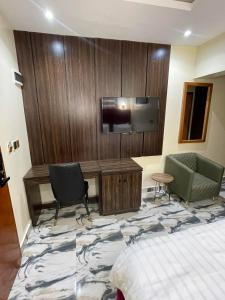 乌约Masters Class Hotels and Apartment的配有一张床和一台平面电视的酒店客房