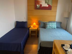 圣保罗Flat de Luxo Aeroporto Congonhas - Hotel eSuites的一间卧室配有两张床和一张带台灯的桌子