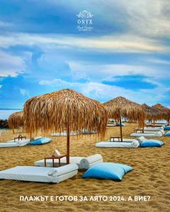 圣弗拉斯Onyx Beach Residence - Free Parking & Beach Access的海滩上配有一些草伞和蓝色枕头