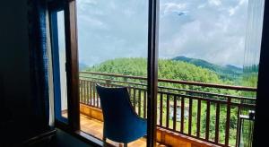 Mai JūbarRadiance valley Resort - A peaceful stay的蓝色椅子坐在阳台,可望见窗外