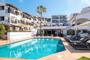 马翁Calallonga Hotel Menorca的大楼前的游泳池