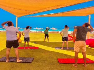 Dawwār ‘Abd al Qādir QāsimBorg El Arab Beach Resort的一群人在海滩上做瑜伽