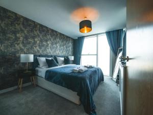 米尔顿凯恩斯The Safari Suite Luxury Apartment Milton Keynes的一间卧室配有一张带蓝色毯子的床和窗户。