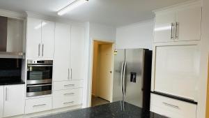 米尔迪拉澳大利亚厄尔利汽车旅馆的厨房配有白色橱柜和不锈钢冰箱