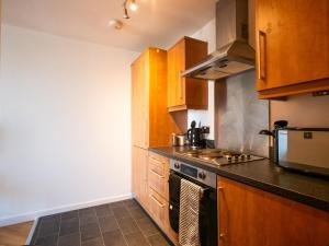 米尔顿凯恩斯The Safari Suite Luxury Apartment Milton Keynes的厨房配有木制橱柜和炉灶烤箱。