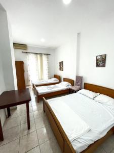 萨兰达Hostel Casa Mia SR的客房设有三张床、一张桌子和一张书桌