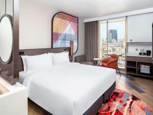 曼谷Mercure Bangkok Surawong的一间带白色大床的卧室和一间客厅