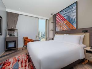 曼谷Mercure Bangkok Surawong的一张大白色的床,位于一个设有大窗户的房间