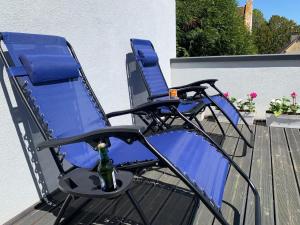 瑟农什Chambres Senonches centre-ville的甲板上的两把蓝色椅子和一瓶香槟