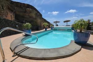 阿索马达Castillo Lanzarote Villa 4 - Sleep in a Volcanic Cave的庭院内种植了盆栽植物的游泳池