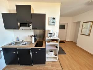 巴特Ostseeland的一间小厨房,配有黑色橱柜和水槽