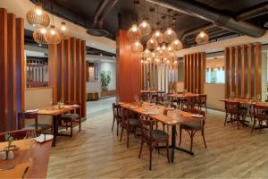 比勒陀利亚Protea Hotel by Marriott Pretoria Hatfield的餐厅设有木桌、椅子和吊灯。