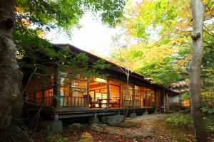 轻井泽鹤屋旅馆 的树林中的房屋,设有玻璃窗