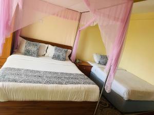MurangʼaHOTEL NOKRAS (K) LIMITED的一间卧室配有两张床和粉红色窗帘