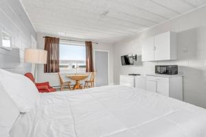 Mavillette海角景观小屋汽车旅馆的白色卧室配有一张大床和一张桌子