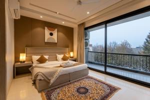古尔冈The Lodgers Luxury Hotel Near Golf Course Road Gurgaon的一间带大床的卧室和一个阳台