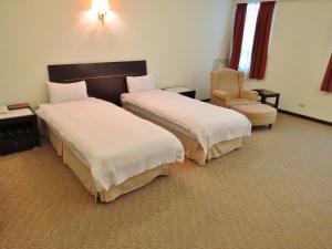台中市禾康商务旅馆的酒店客房,配有两张床和椅子