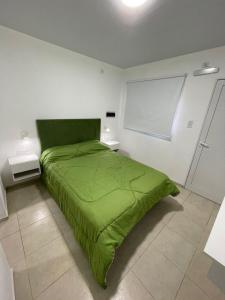 RufinoHostería Tere的白色客房的一张绿色床,设有窗户