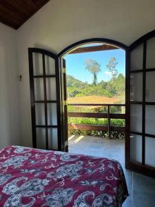 迈林克Chácara condomínio Porta do Sol的卧室设有开放式门,享有树木美景