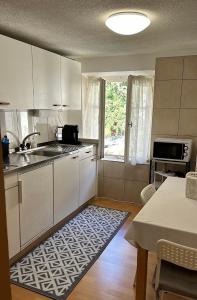 EnnendaBom descanso的厨房配有白色橱柜、桌子和厨房地毯。