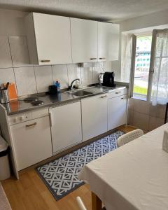 EnnendaBom descanso的厨房配有白色橱柜、水槽和桌子