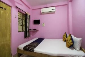 贾姆谢德布尔OYO Hotel Suvidha的卧室拥有粉红色的墙壁,配有带枕头的床铺