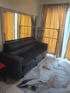 雅加达Apartemen city home gading riview的窗户客房内的黑色皮沙发