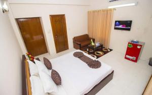 达卡Hotel Suite Palace Baridhara的一间卧室配有一张床、一把椅子和电视