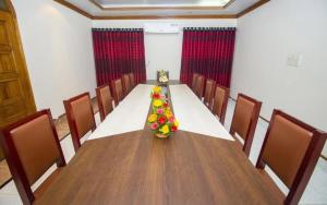 达卡Hotel Suite Palace Baridhara的一间会议室,里面摆放着长桌子和鲜花