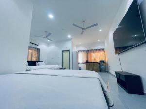 AdentanRakka Guest House的一间白色卧室,配有两张床和电视