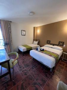 瓜达拉哈拉Hotel Flamingos的酒店客房设有两张床和一张桌子。