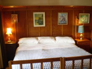 奥玛鲁联邦住宿加早餐旅馆的卧室内的一张床位,配有两盏灯和墙上的照片