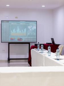 齐克拉约Hotel America Chiclayo的一间会议室,配有两张桌子和投影屏幕