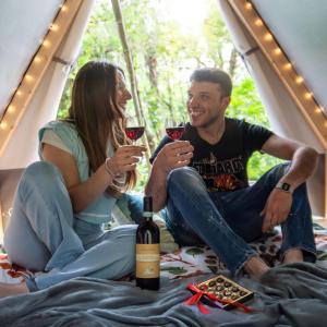 热那亚Glamping Montecontessa by SMART-HOME, Tipì的坐在帐篷里的男人和女人喝酒